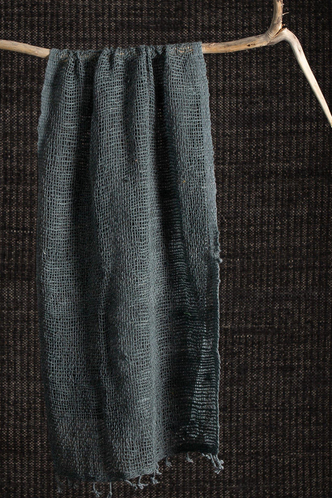Dark green fabric draped over a wooden stick against a dark background