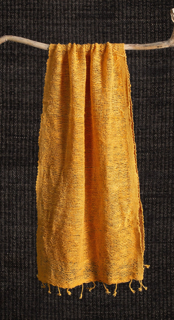 Mustard yellow scarf on a wooden hanger against a black background