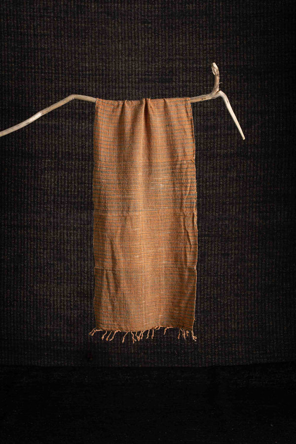 Brown woven fabric draped over a branch against a dark background