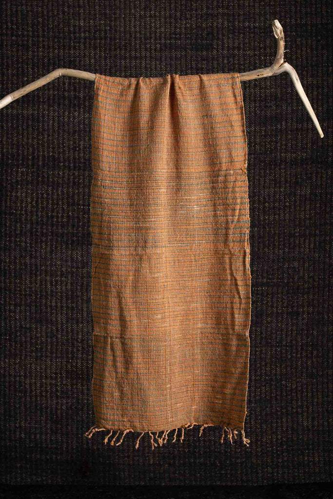 Brown woven fabric draped over a branch against a dark background